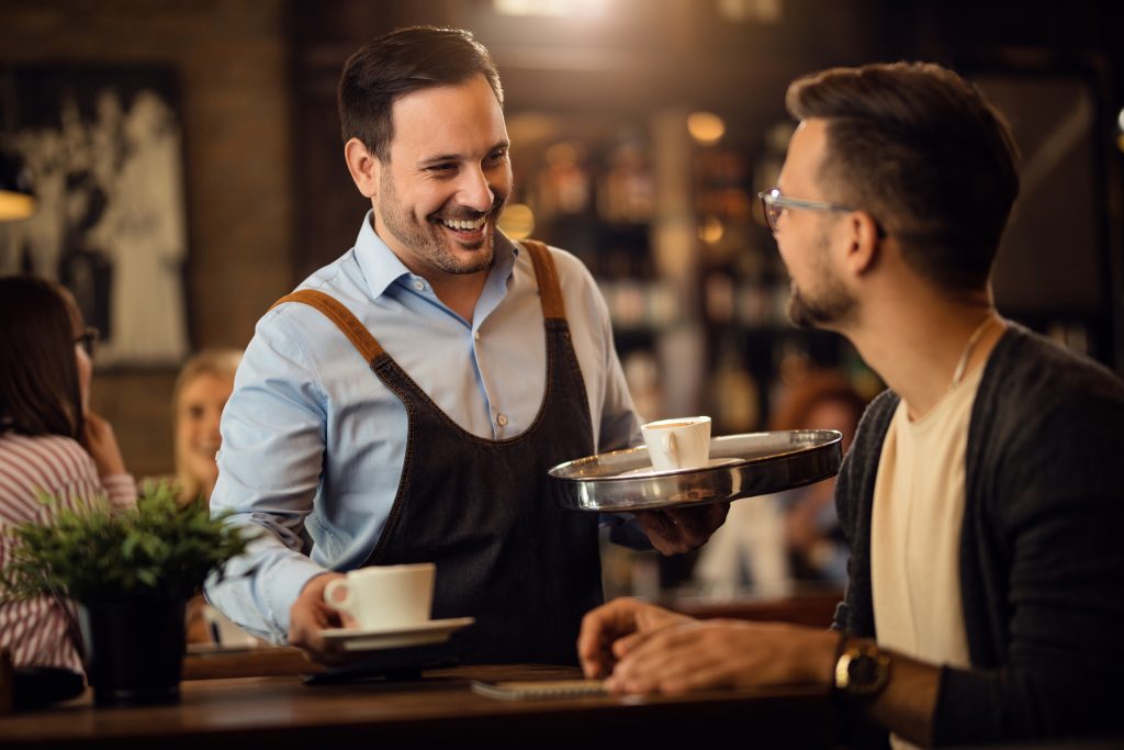 camarero-feliz-sirviendo-cafe-comunicandose-invitado-masculino-bar-1024x683