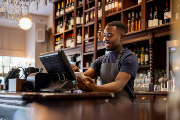 Happy waiter working at a restaurant and placing an order in the system using a computer